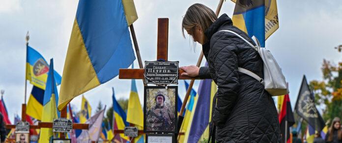 Non Exclusive: LVIV, UKRAINE - OCTOBER 28, 2023 - A woman looks at the photograph of a perished Ukrainian soldier on the graveside cross in the field